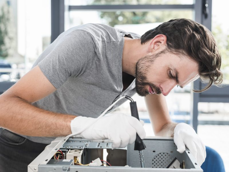 side-view-young-male-technician-working-broken-computer